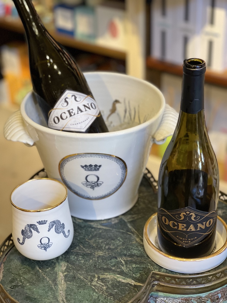 Oceano ice bucket, bottle coaster, and wine goblet depicted with Oceano Chardonnay and Pinot Noir wine bottles.