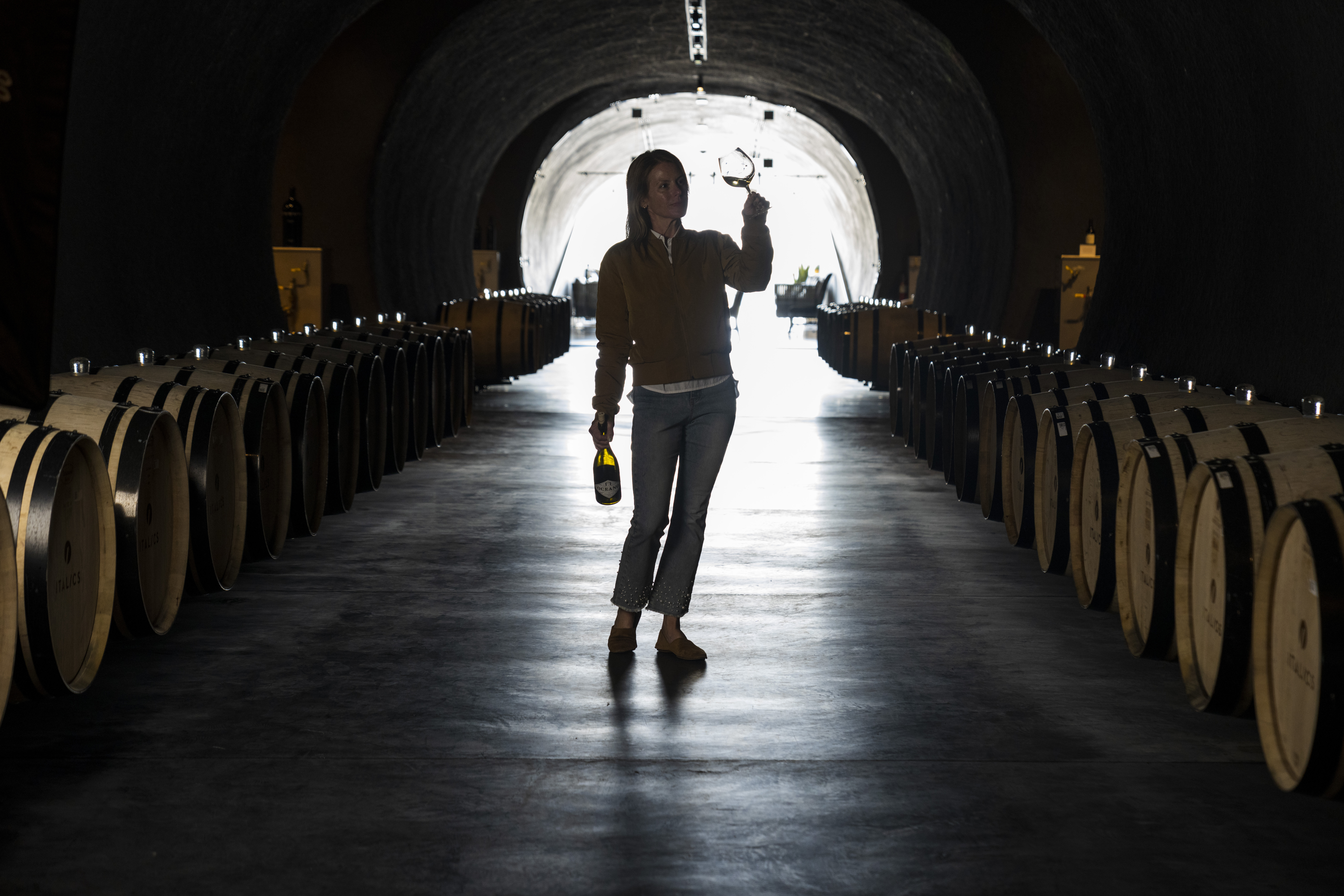 Rachel Martin in winery tunnel swirling glass of wine