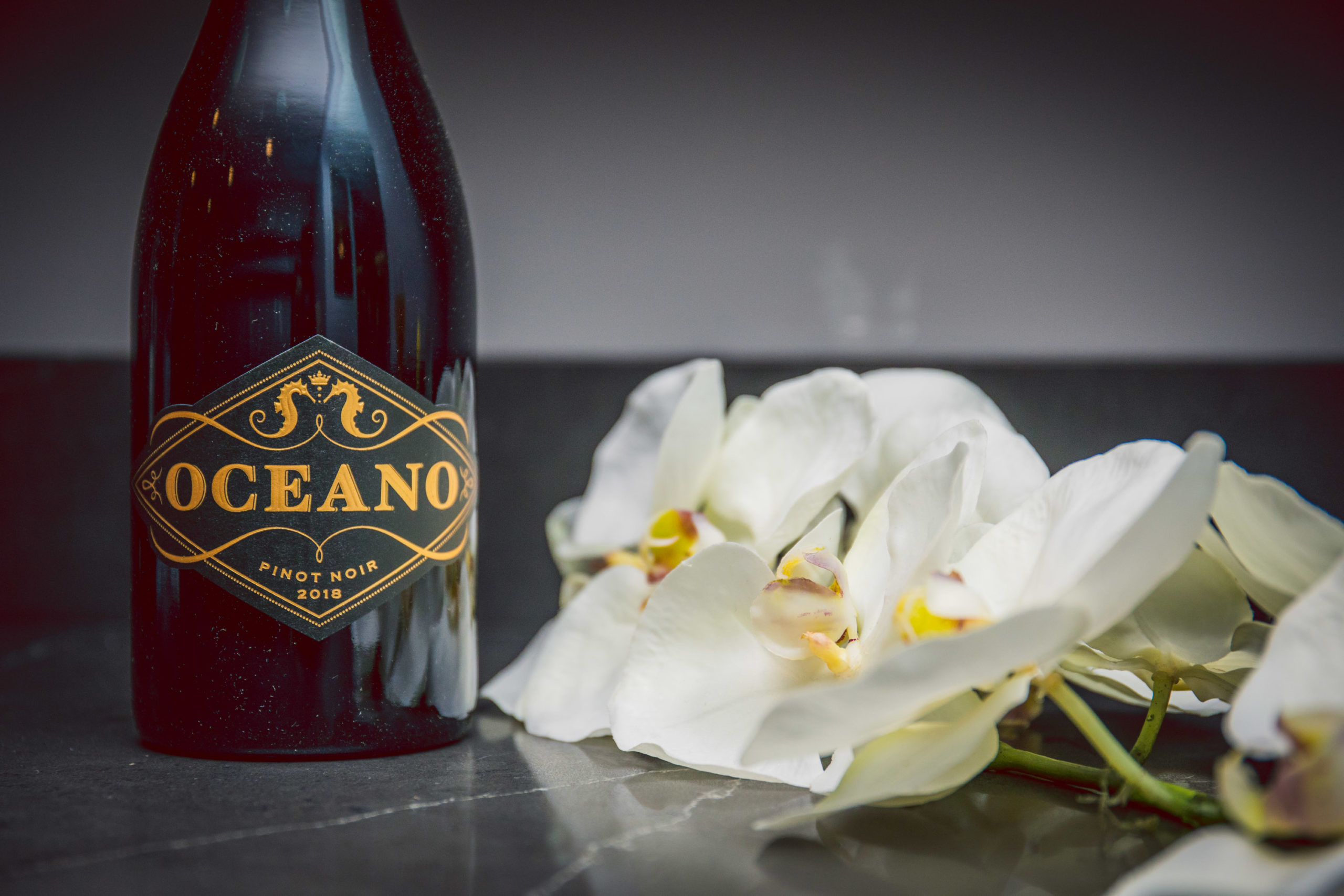 flowers on floor next to Oceano Pinot Noir bottle