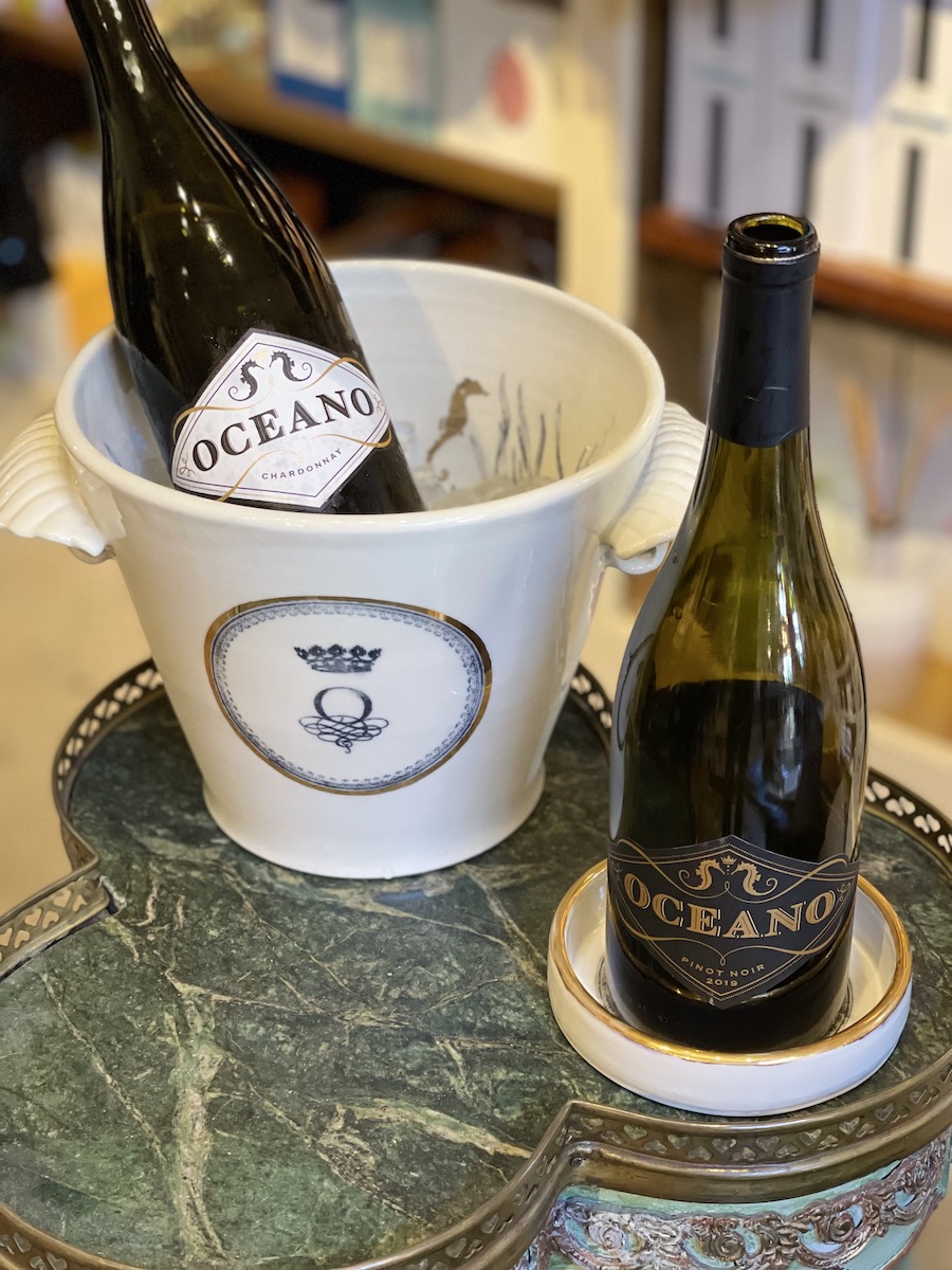 Oceano ice bucket and wine bottle coaster depicted with bottles of Oceano Chardonnay and Pinot Noir wines.