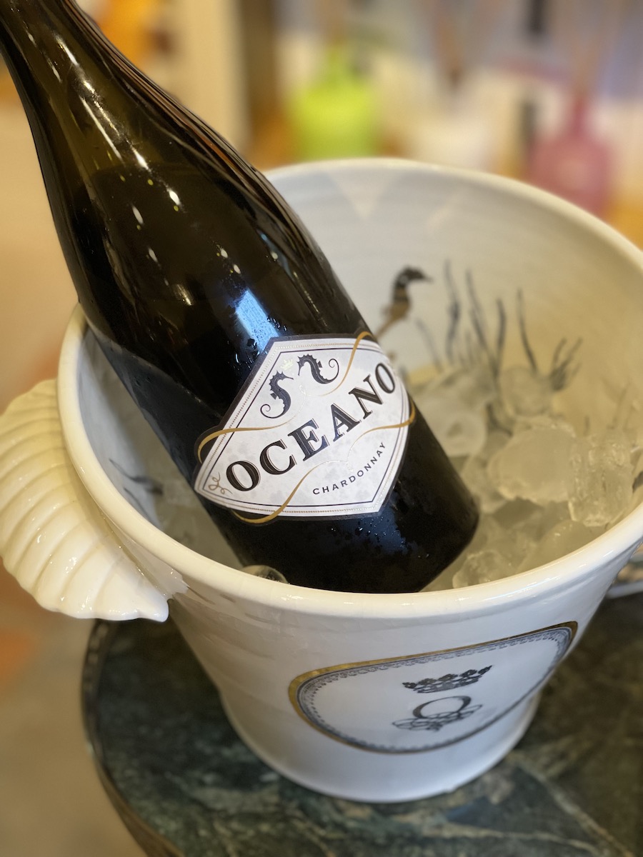 Bottle of Oceano Chardonnay wine chilling in white Oceano ice bucket.