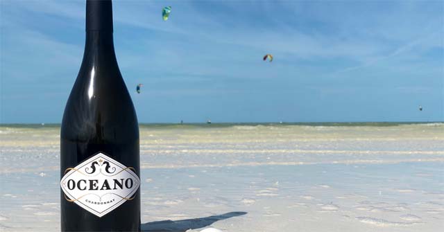 A bottle of Oceano Chardonnay wine on a beach