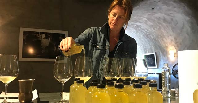A woman pouring wine into a row of glasses