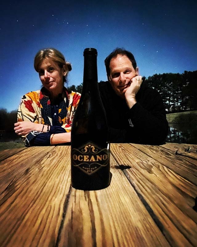 A couple posing behind a wine bottle