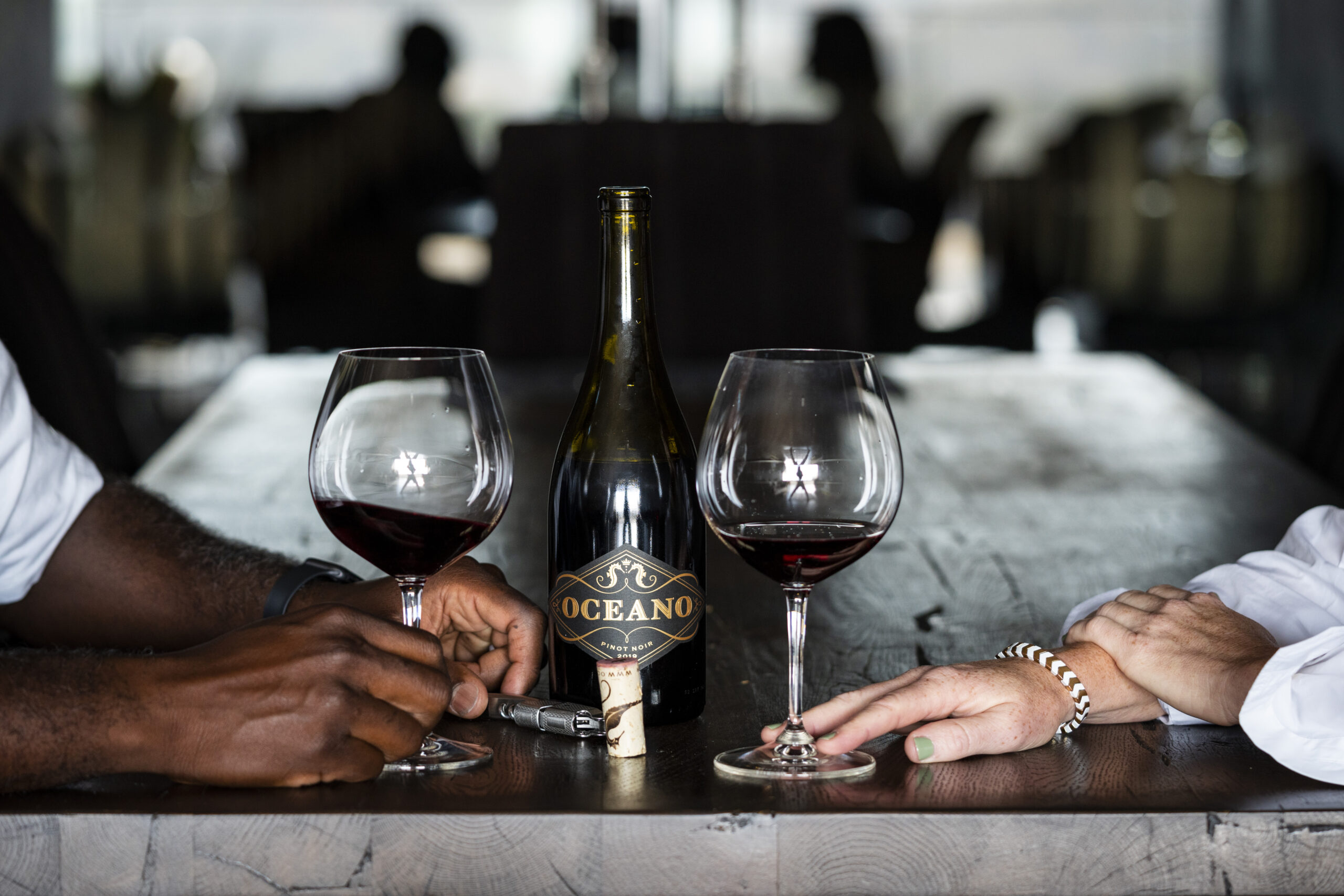 two people drinking Oceano Pinot Noir together at table