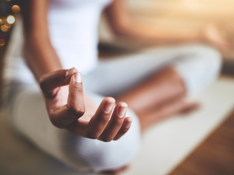 Image Of the Lower Half Of A Woman Who Is Dressed In White Yoga Clothes And Sitting On A White Mat Who Appears To Be Meditating. Image Is Shown In Conjunction With Our CA Non-alcoholic Wine Company's blog post about mindful drinking/drinking mindfully.