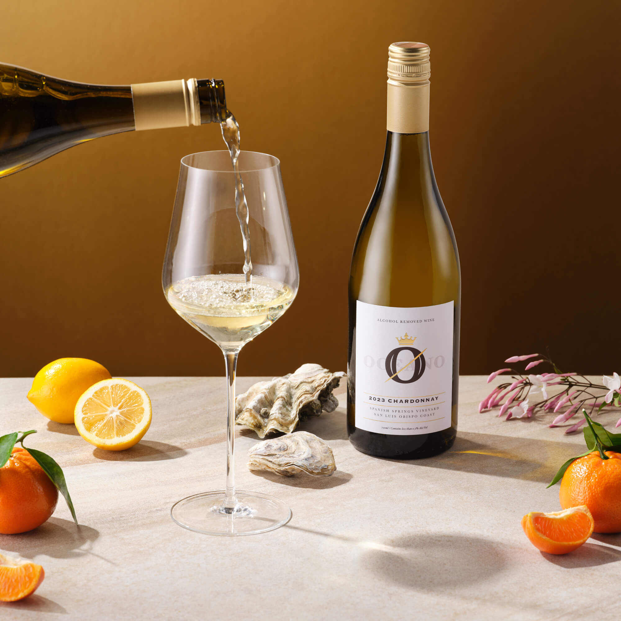 A table with a bottle of Oceano Zero chardonnay wine, a non alcoholic wine, being poured into a wine glass.