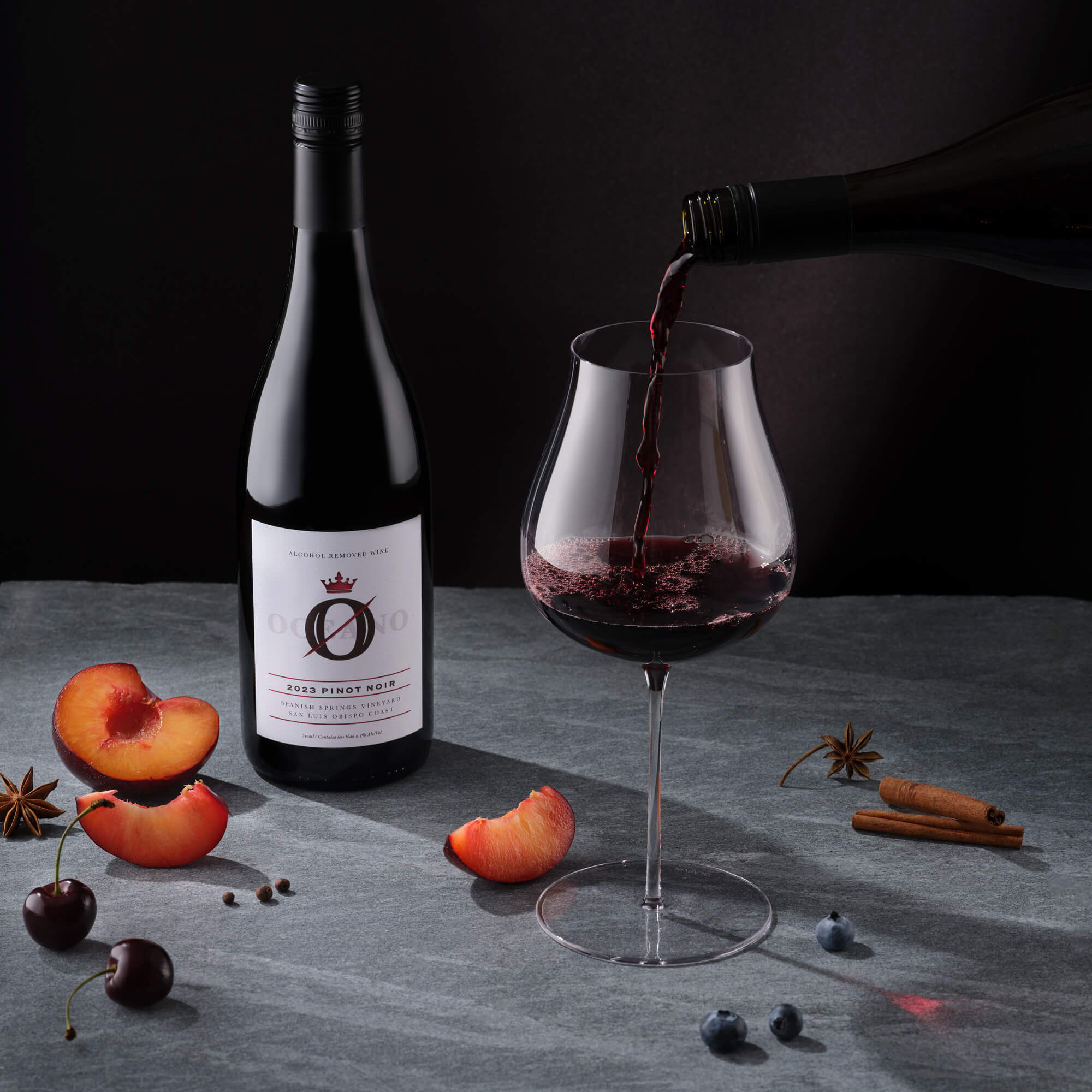 A table with a bottle of Oceano Zero Pinot Noir, a dealcoholized wine being poured into a red wine glass.