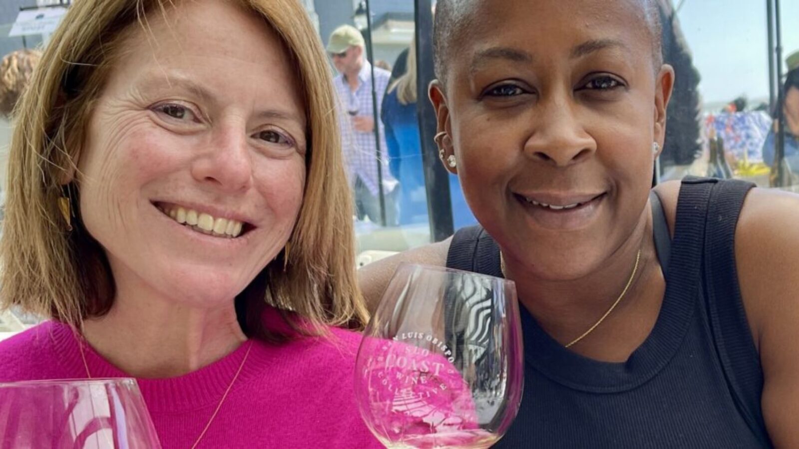 Two women smile as they hold wine glasses.