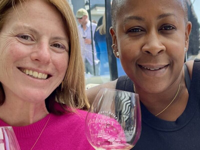 Two women smile as they hold wine glasses.