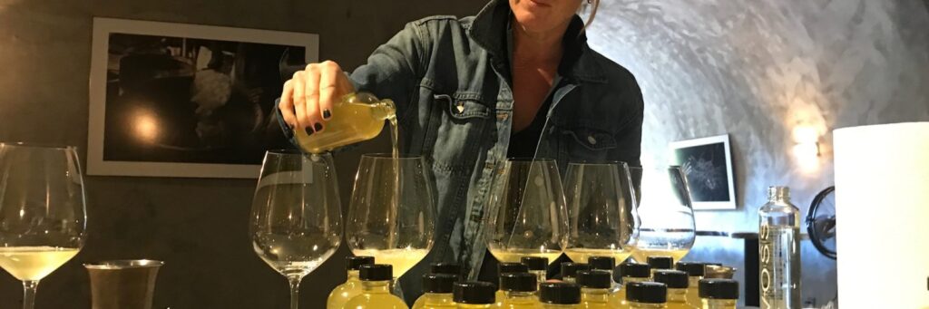 A woman pours white wine into wine glasses.