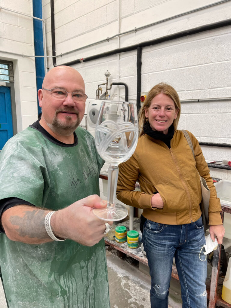 A woman smiles as she looks at a wine glass held by a smiling man.