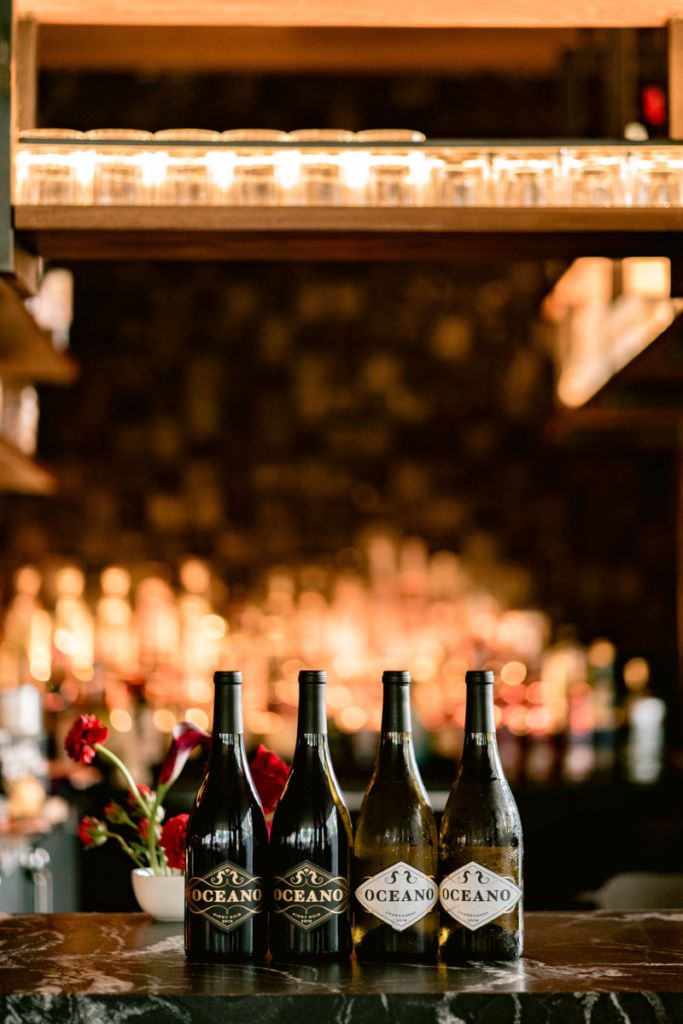 Four bottles of Oceano wine on the marble counter of a bar.