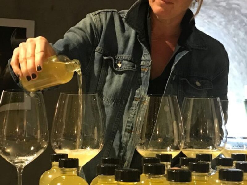 A woman pours white wine into wine glasses.