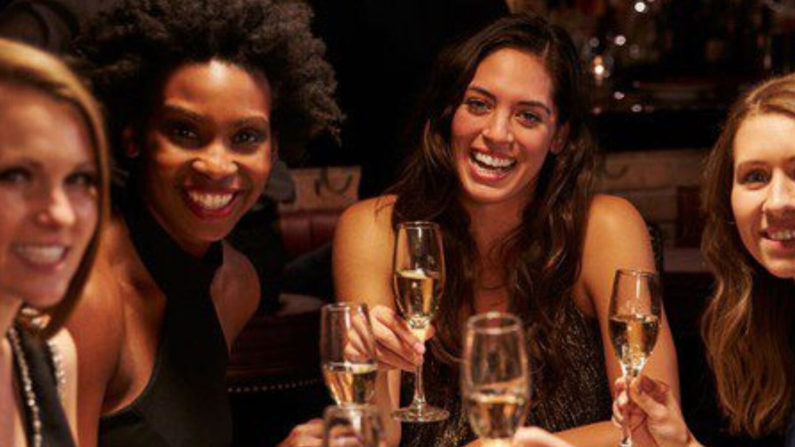 Four women smile as they hold champagne glasses.