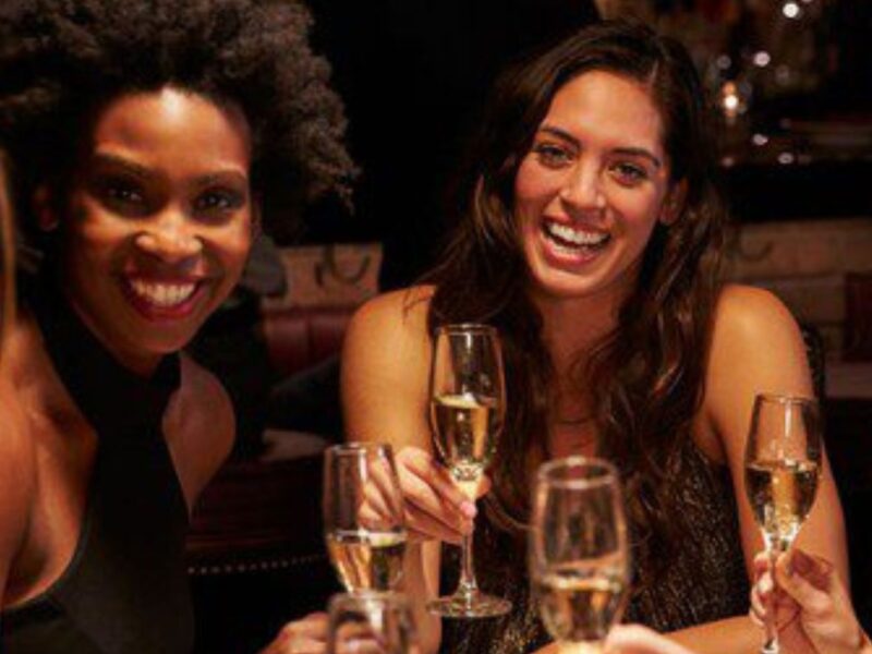 Four women smile as they hold champagne glasses.