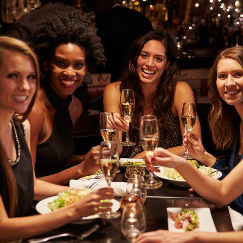 Four women smile as they hold champagne glasses.