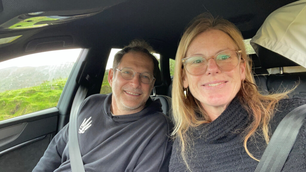 A man and a woman smile as they sit in a car.