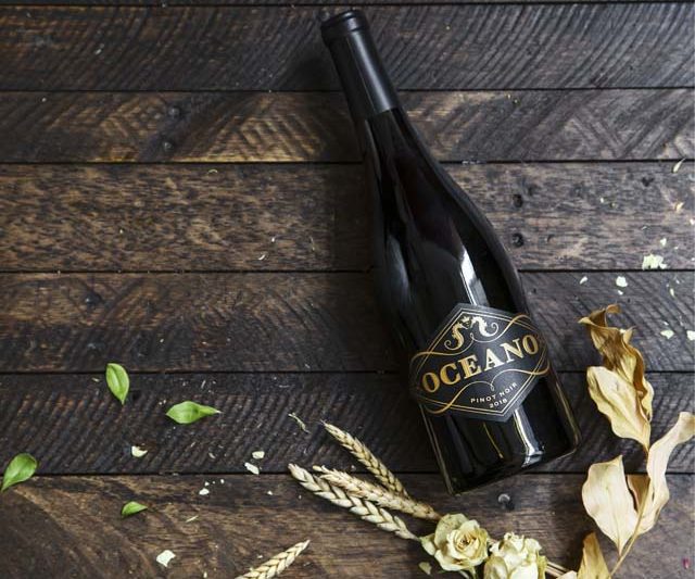 A bottle of Oceano Wines' Pinot Noir from the 2018 vintage resting on a wooden surface.