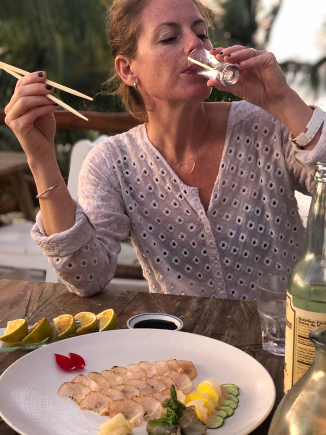 Rachel Martin, the owner of Oceano Wines, sipping a shot while enjoying seafood on a Mexican beach.