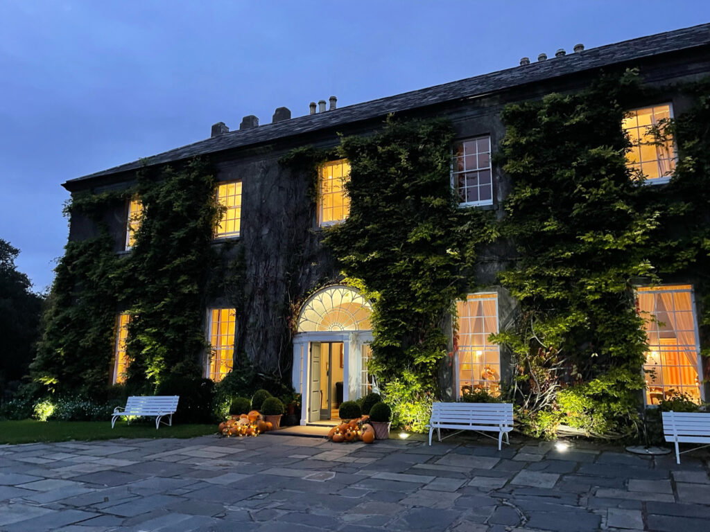 A stone building with ivy growing on it at dusk.