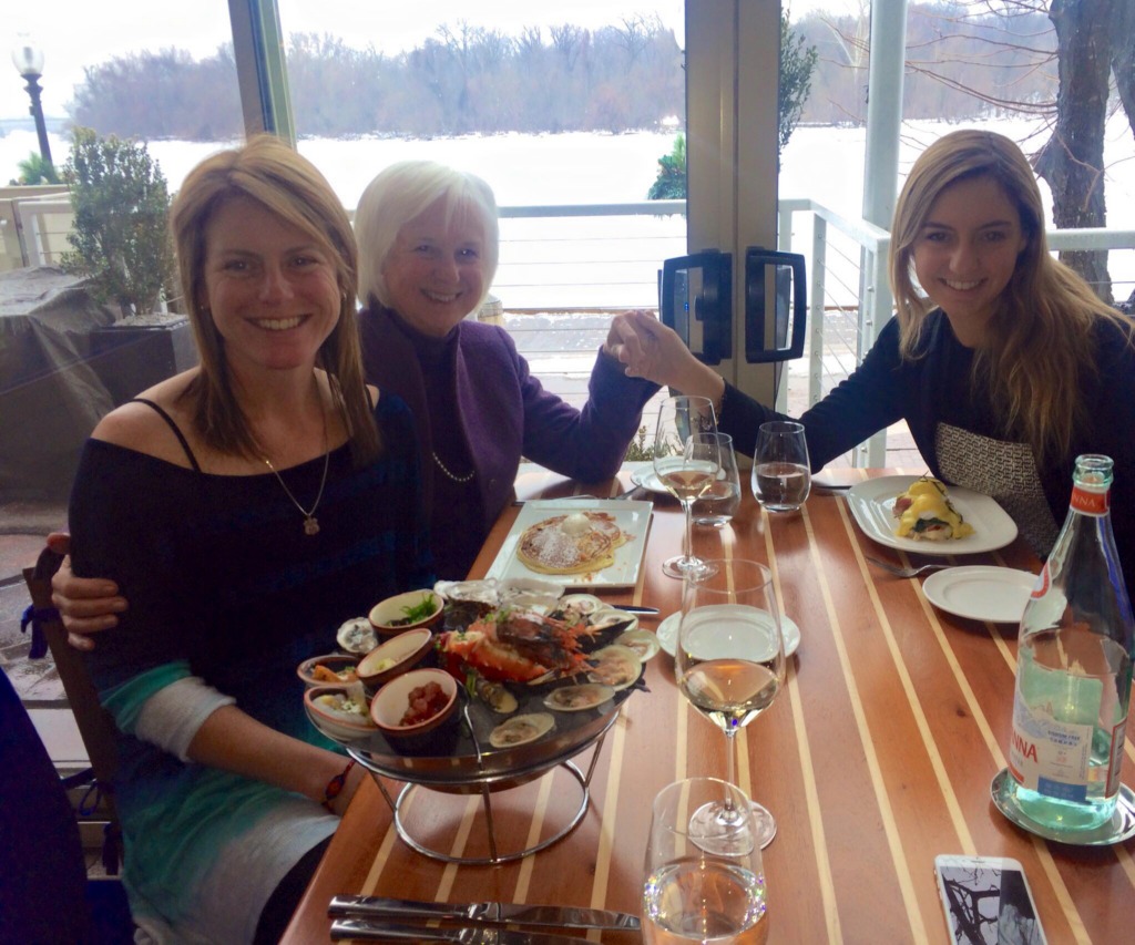 Three women at a seafood restaurant enjoying a seafood tower and white wine.