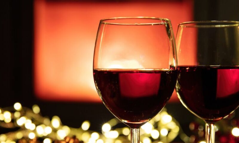 Two glasses of red wine sitting in front of green and red lights.