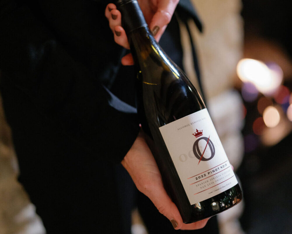 Rachel Martin holding a bottle of oceano zero pinot noir.