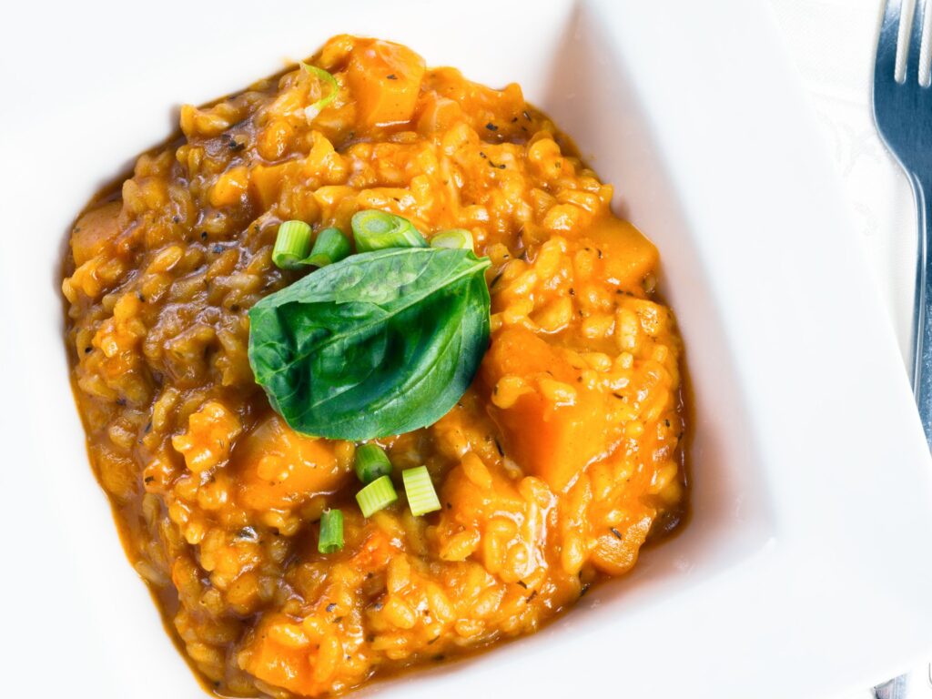 Fall recipe of butternut squash risotto in a bowl, golden roasted squash and herbs